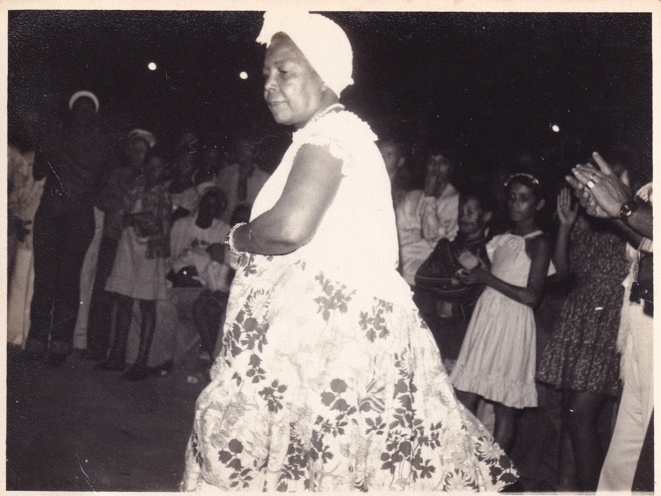 foto em preto e branco de uma mulher negra com saia de fita e turbante dançando