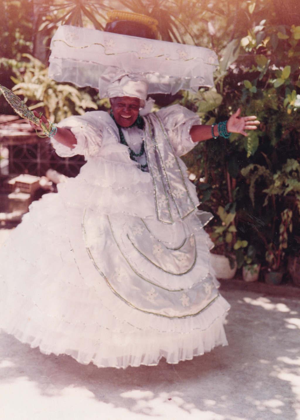 foto em preto e branco de uma mulher negra com saia de fita e turbante dançando