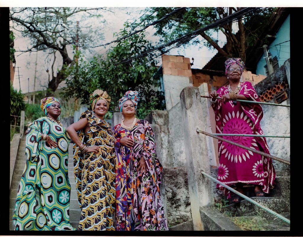 Um grupo de mulheres com vestidos coloridos em pé nos degraus.