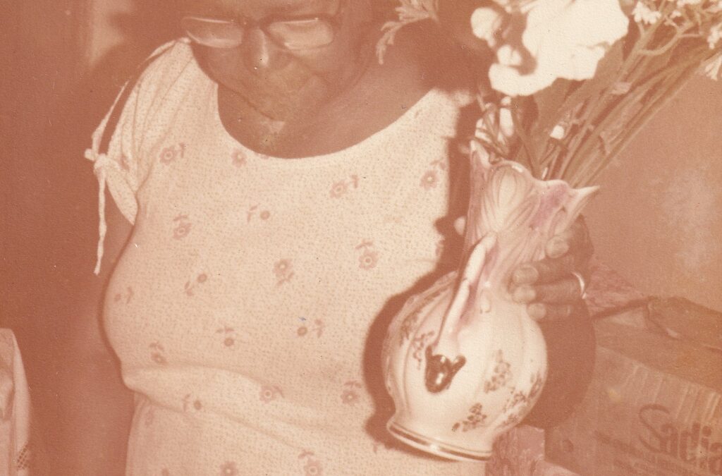 Tia Maria em sua casa segurando um vaso de flores
