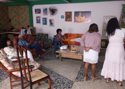 Um grupo de pessoas se reuniu em uma sala comunitária com móveis estampados e decoração nas paredes.