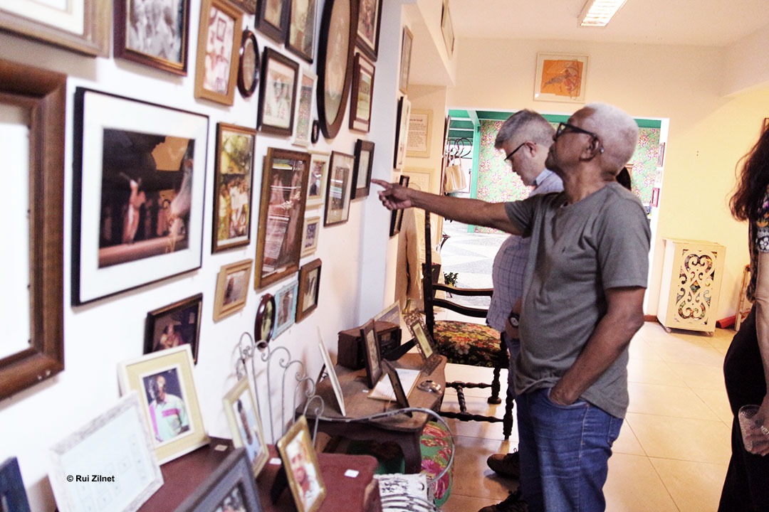 Dois homens observando a parede de uma galeria coberta de fotografias emolduradas.