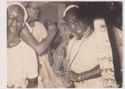 Fotografia vintage em preto e branco de três mulheres usando lenços brancos na cabeça e colares em uma reunião.